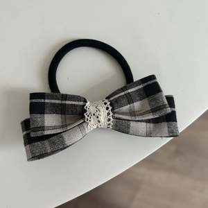 Detail of grey plaid bow scrunchie featuring delicate white crochet lace trim