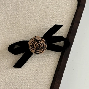Detail of elegant black velvet bow hair clip with leopard print fabric rose flower center