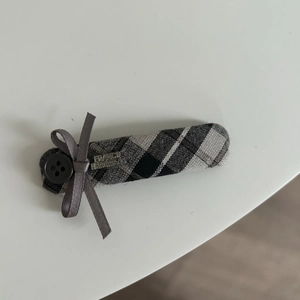 Detail of grey plaid hair clip with bow, button, and France Handmade metallic tag