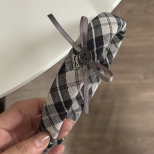 Detail of British style grey plaid headband with ribbon bow and button ornament