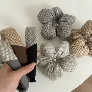 Detail view of plaid fabric headbands and scrunchies featuring central pearl embellishments