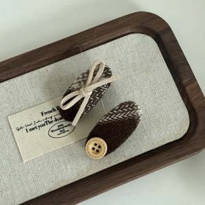 Detail of British style brown plaid hair clips with bow and wooden button decoration