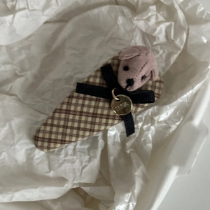 Detail of plaid hairpin with a pink plush bear, black ribbon bow and gold LUNA tag