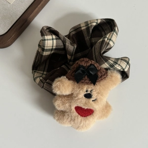Détail d'un chouchou ours en peluche avec tissu à carreaux et broderie de cœur