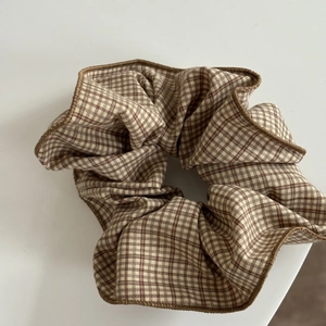 Close-up of vintage brown gingham plaid scrunchie with detailed stitching and soft cotton texture