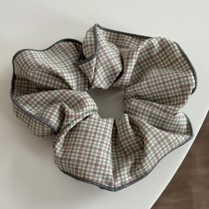 Detailed macro view of the plaid scrunchie showing green and beige woven fabric texture
