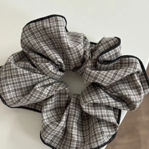 Macro detail of plaid fabric scrunchie with high-quality black stitched edges and gray pattern