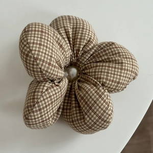 Detailed macro view of a brown plaid flower hair scrunchie with a large pearl center