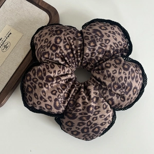 Macro detail of large leopard print hair scrunchie with black lace edging in flower shape