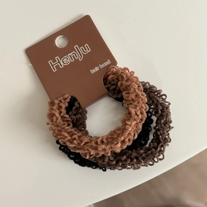 Detail shot of three elastic hair bands in black and brown on a minimalist paper card