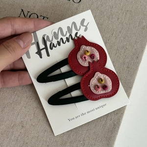 Close-up of handmade red pomegranate leather hair clips with colorful beads for girls