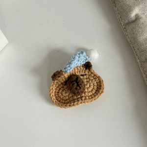 Handgefertigte Häkel-Capybara-Haarklammer mit blauer Strickmütze und Plüschkugel