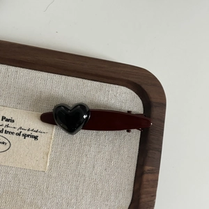 Retro wine red hair clip with black heart accent on a vintage display board
