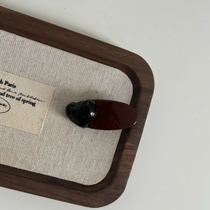 Vintage dark wine red hair clip with black heart detail on a wooden display tray