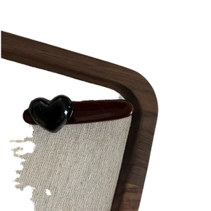 Vintage burgundy hair clip with black heart detail on wood tray and beige fabric texture