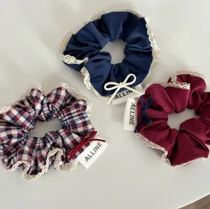 Three stylish plaid and lace scrunchies in navy and wine red with bows and tags