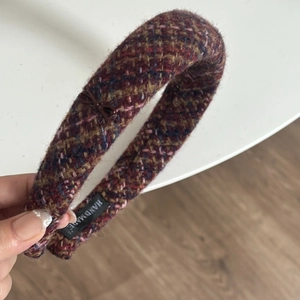 Detail of multi-color plaid tweed headband with handmade label and brown bow decoration