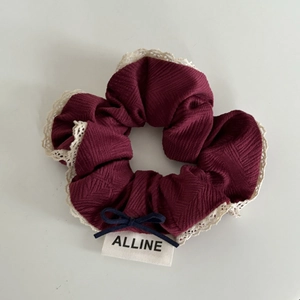 Macro view of burgundy plaid hair scrunchie with cream lace trim and bow detail