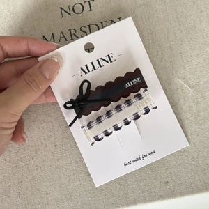 Detail view of two bow hair clips in brown and blue plaid patterns on display card