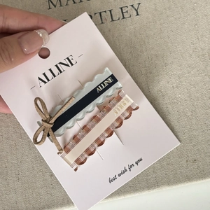 Detail view of two stylish bow hair clips with brown and gray wave designs on a card