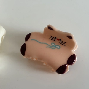Detail der rosa Katzen-Haarklammer mit niedlichem Gesichtsausdruck und blauem Band