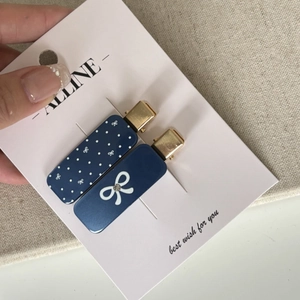Detailed shot of two blue bow hair clips with polka dots and rhinestones on card