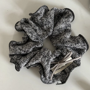 Détail d'un chouchou en tricot gris avec étiquette faite main et texture de laine