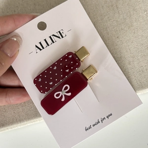 Close-up of deep red bow hair clips with polka dots and rhinestones on card