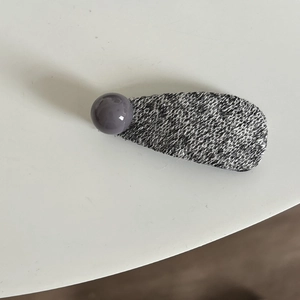 Détail d'une pince à cheveux en tricot gris avec une perle décorative violette chic