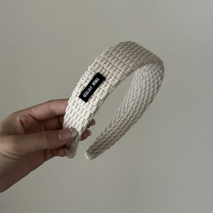 Detail of cream knitted headband featuring waffle texture and a True Fitted label