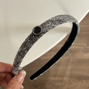 Détail d'un serre-tête tissé gris avec bouton noir vintage et ornement en métal argenté