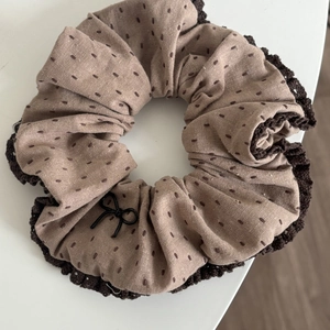 Close-up of brown fabric scrunchie with dot embroidery and crochet lace edge
