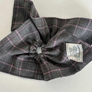 Detail of pink and grey plaid scrunchie with bow tie and fabric care label