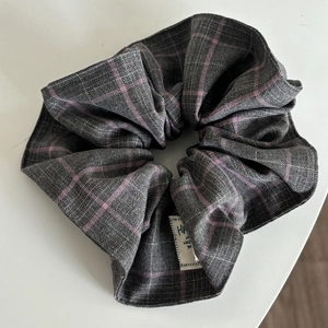 Pink and grey plaid scrunchie with woven fabric and detailed hand wash care label