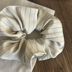 Close-up of a striped cream and grey scrunchie showing detailed cotton fabric texture