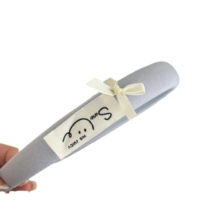 Hellblaues Stoff-Haarband mit weißer Schleife und HIS JUICY Webetikett-Accessoire