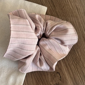 Pink striped fabric scrunchie with soft cotton texture on a natural wooden background