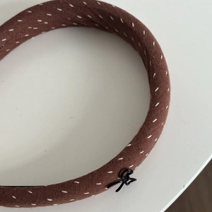Detail of coffee brown fabric headband with white line patterns and small metal bow