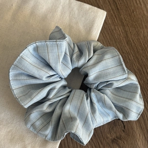 Detailed view of the striped fabric texture on the light blue scrunchie hair tie