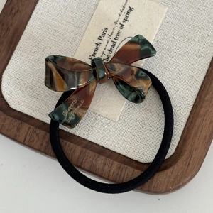 Bow hair tie with acetate tortoiseshell texture and golden lettering on cotton cloth