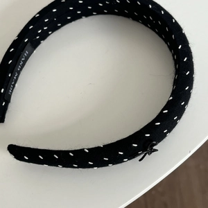 Black fabric headband with white contrast stitching and a handmade woven label