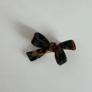 Detailed macro view of an acrylic bow hair claw clip with a dark tortoise pattern