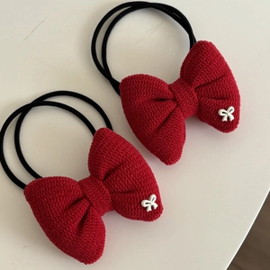 Detail of red knit bow hair ties with woven texture and small white bow accents
