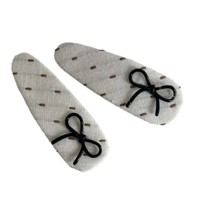Linen fabric hair clips with brown embroidery and black bows on a white background