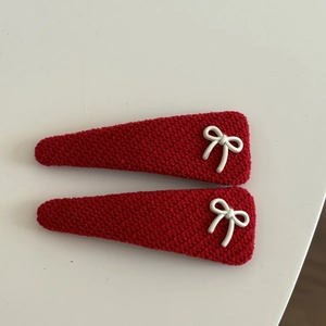 Close-up of red knitted hair clips with white metal bows for elegant hairstyling