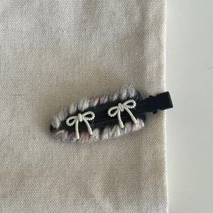 Detail of woven fabric bow hair clip featuring mixed yarn and delicate white ribbon knots