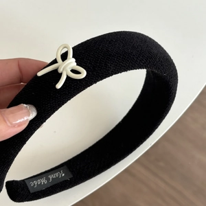 Close-up of handmade black padded sponge headband with a 3D white bow detail