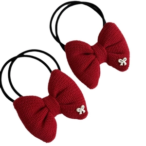 Two red knitted bow hair ties with white resin butterfly accents on plain background