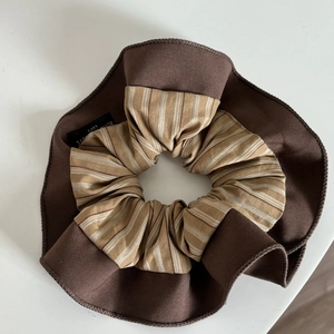 Detailed close-up of navy striped scrunchie with contrasting brown trim and woven label