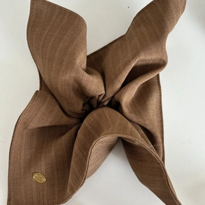 Brown striped fabric scrunchie with elegant golden logo charm for low ponytail hairstyles